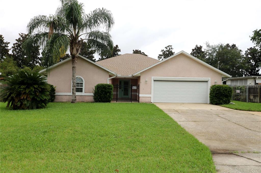 a view of a white house with a yard and palm trees