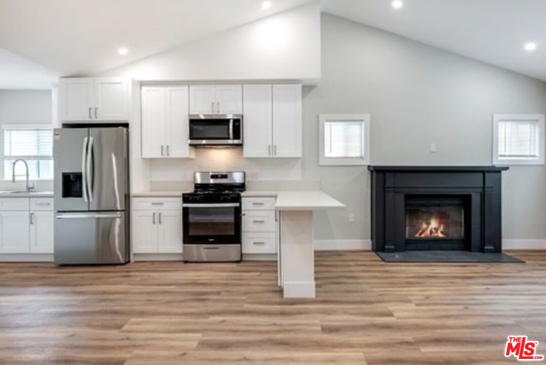 a kitchen with granite countertop a refrigerator and a stove top oven