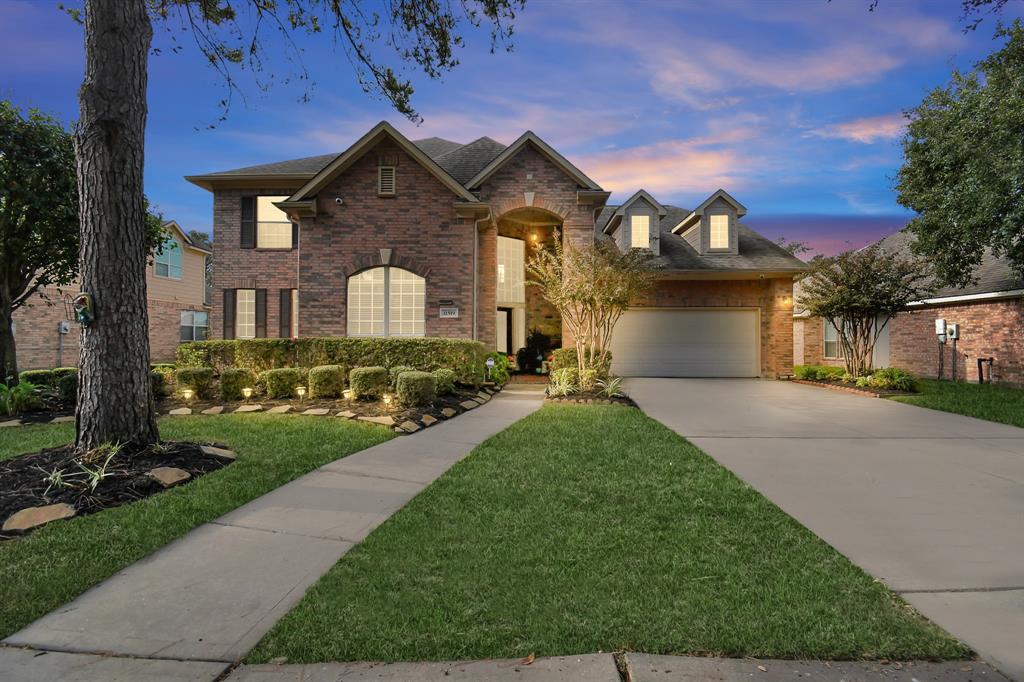 This two-story home shines beautifully at sunset, highlighting its charming architecture and serene front garden under the warm glow of twilight.