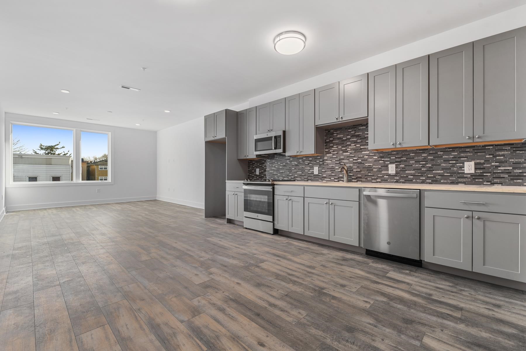 a kitchen with stainless steel appliances granite countertop a stove a sink and white cabinets with wooden floor