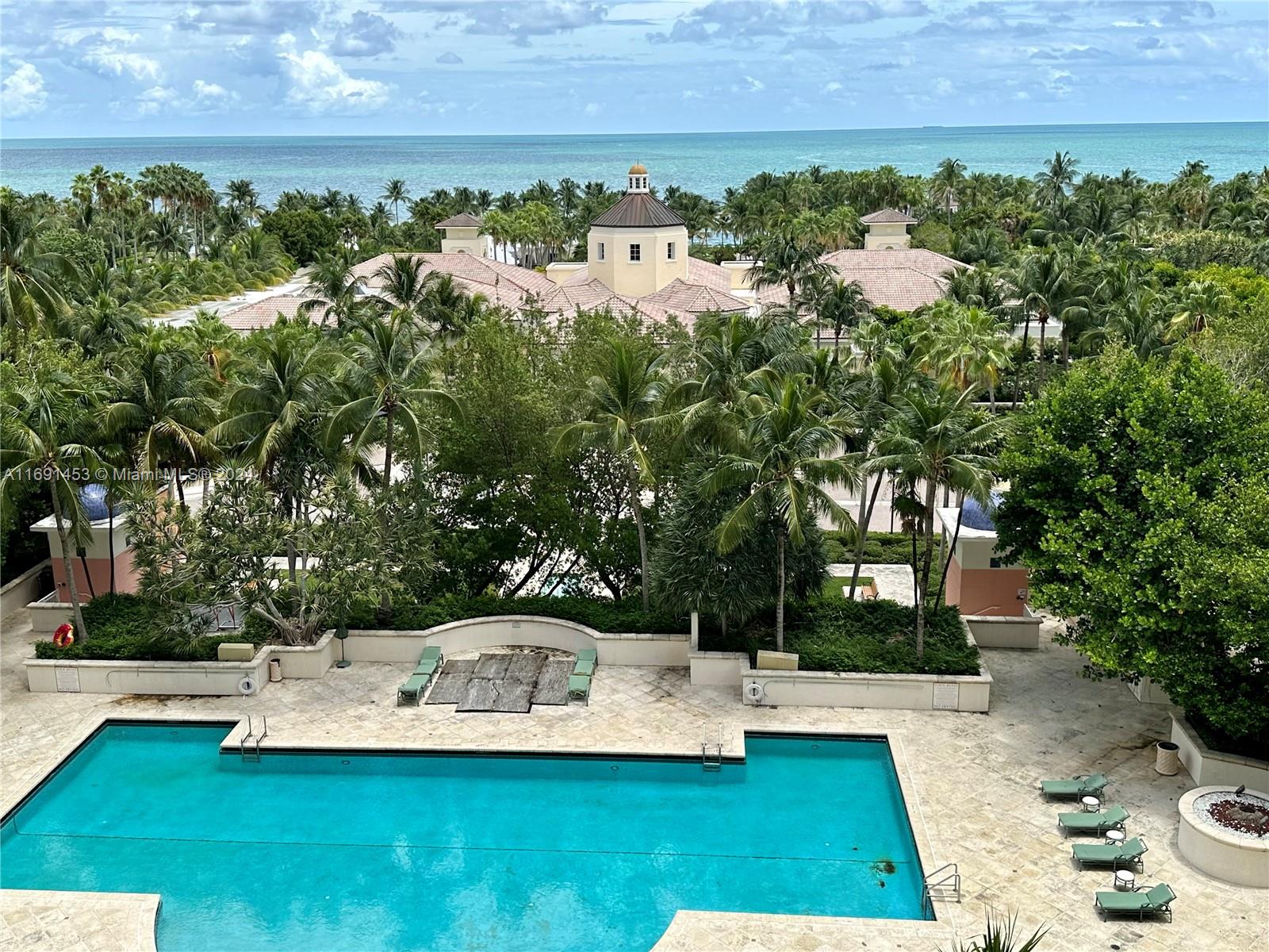 a view of a swimming pool with lawn chairs and plants