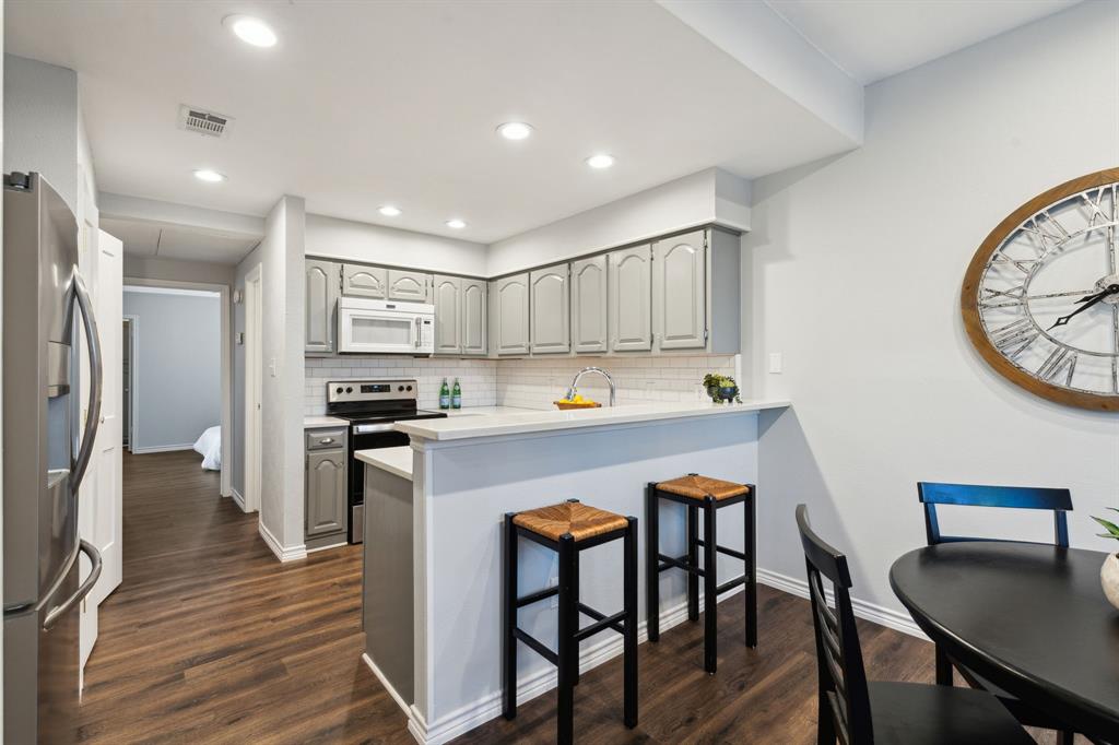 a kitchen with stainless steel appliances a table chairs refrigerator and wooden cabinets