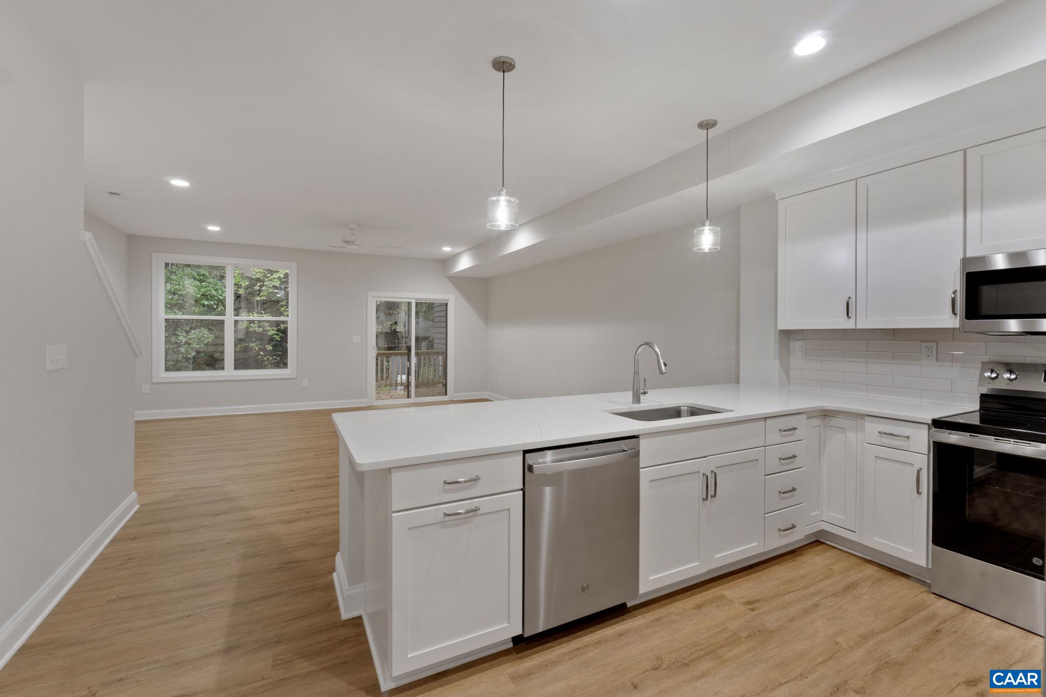 a kitchen with white cabinets appliances and a window