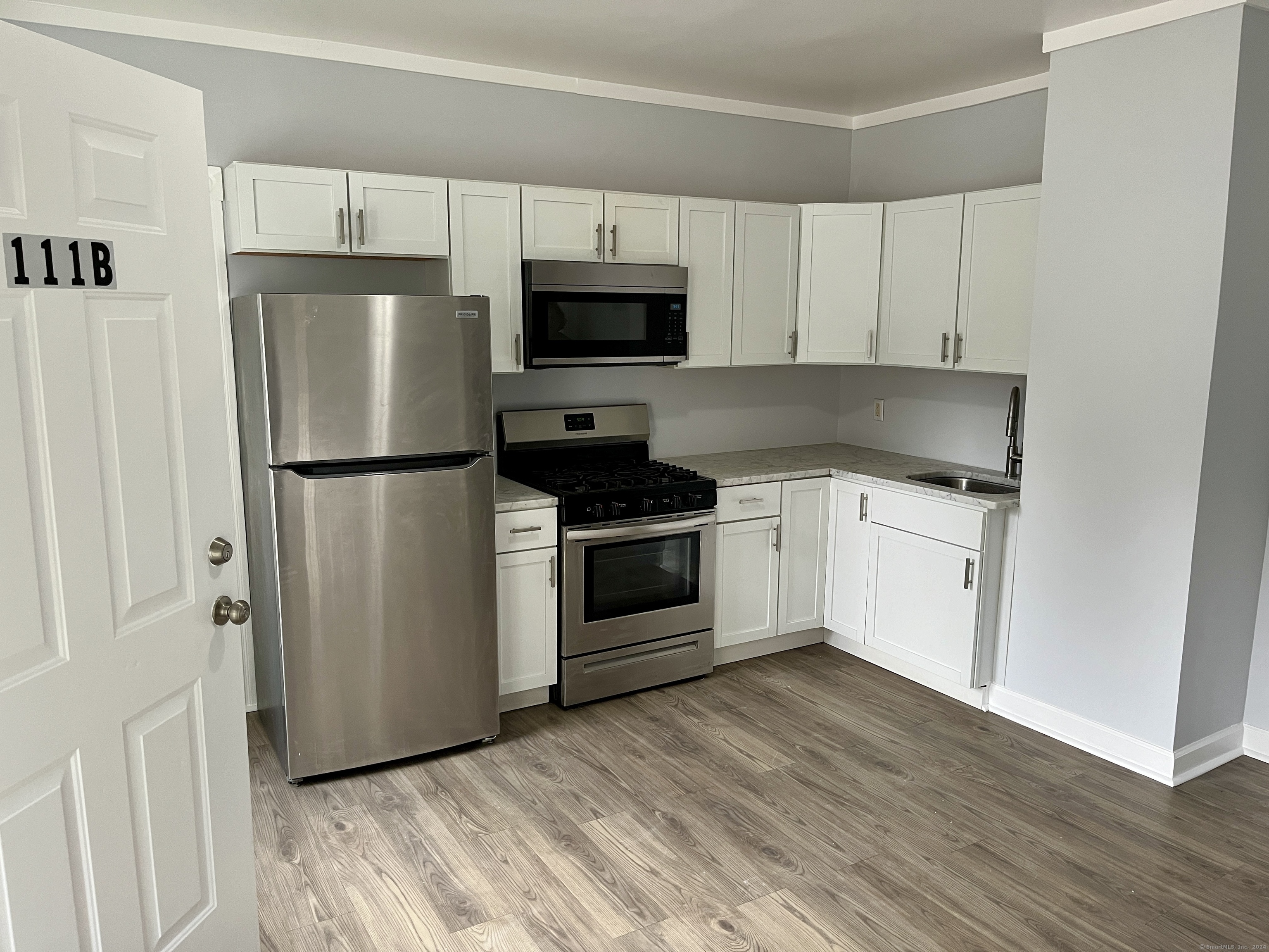 a kitchen with cabinets stainless steel appliances and wooden floor