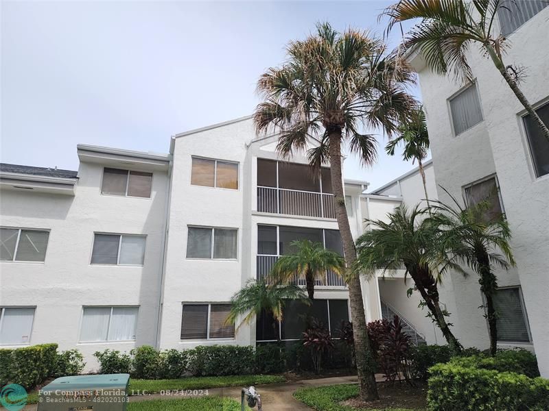 a front view of multi story residential apartment building with yard and parking