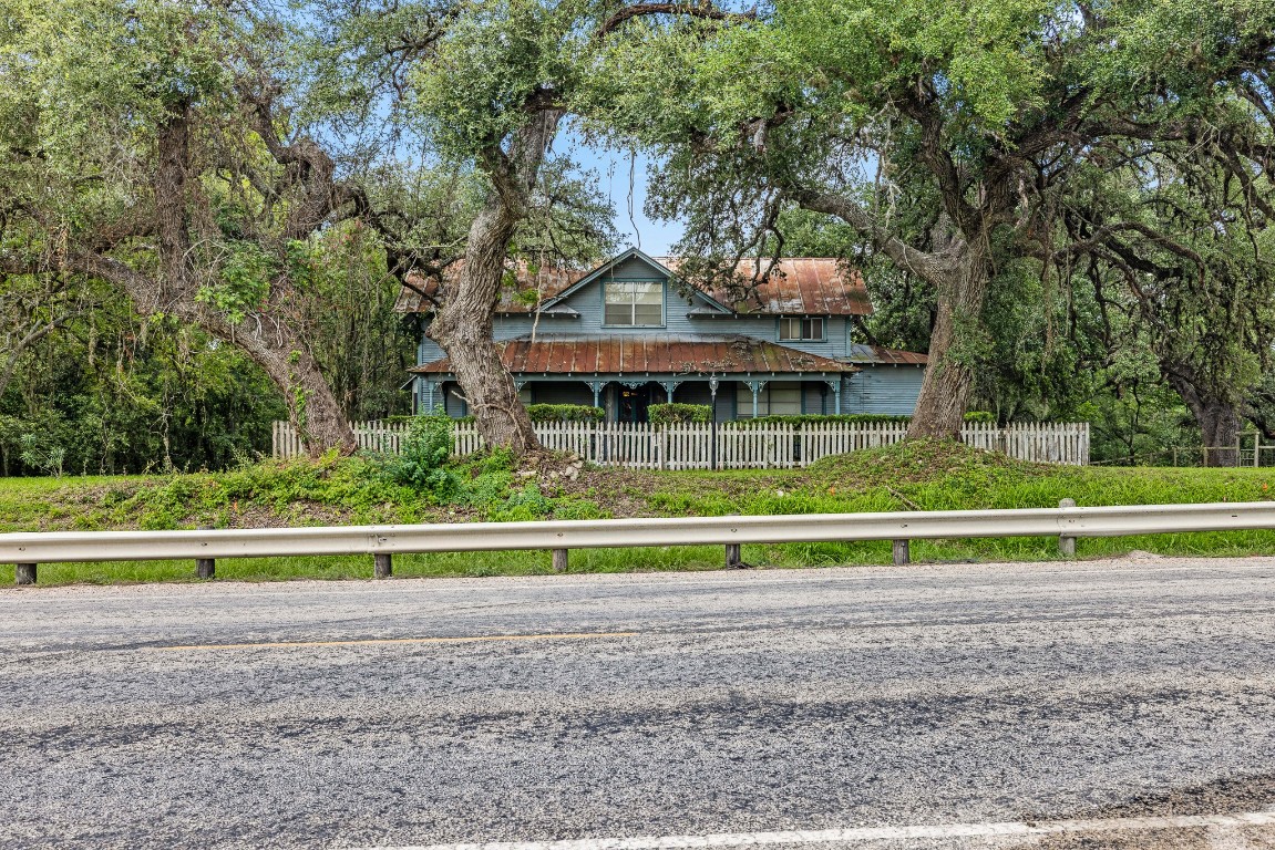 a view of house with a big yard and large trees