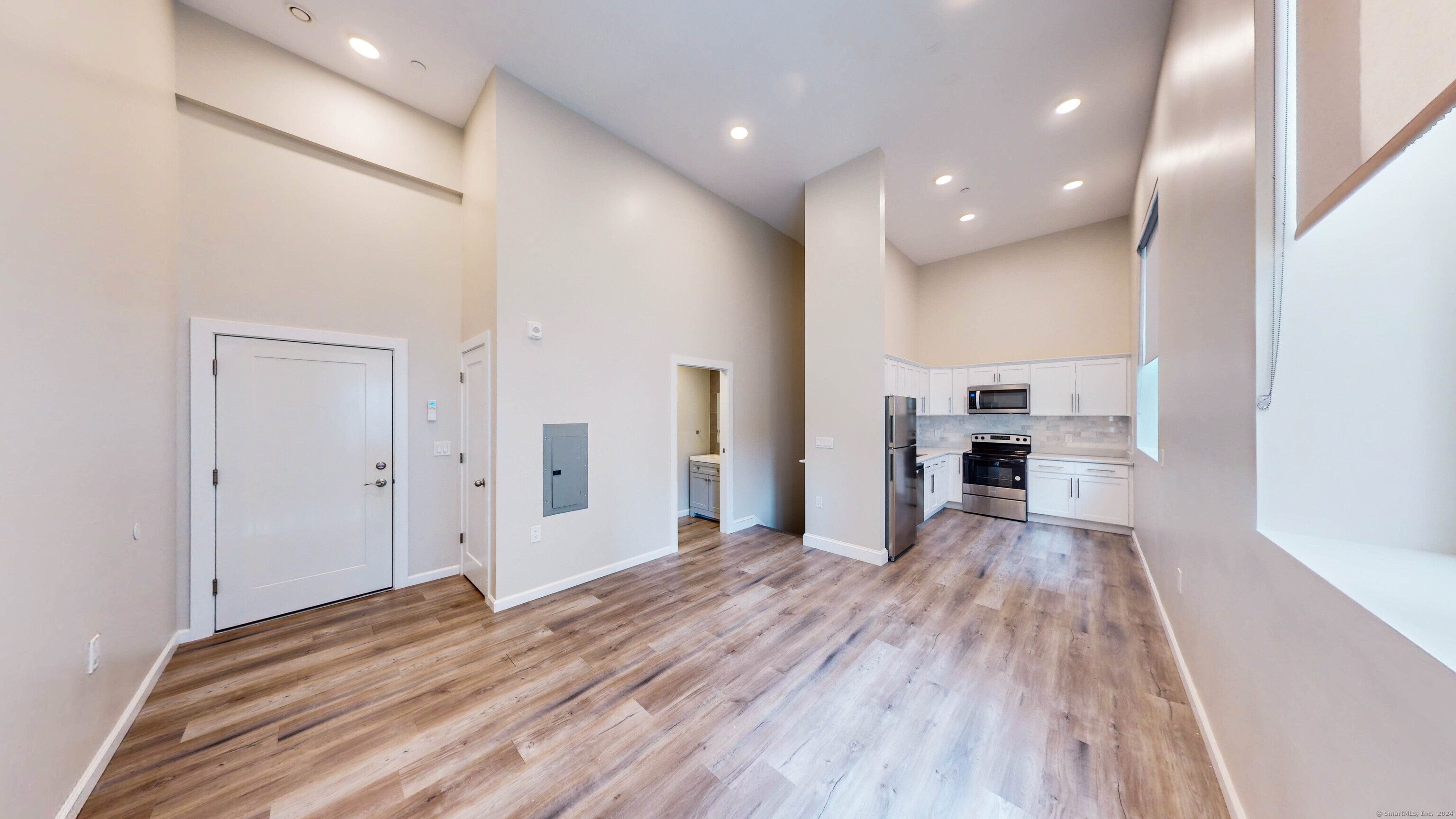 a view of empty room with kitchen and fireplace