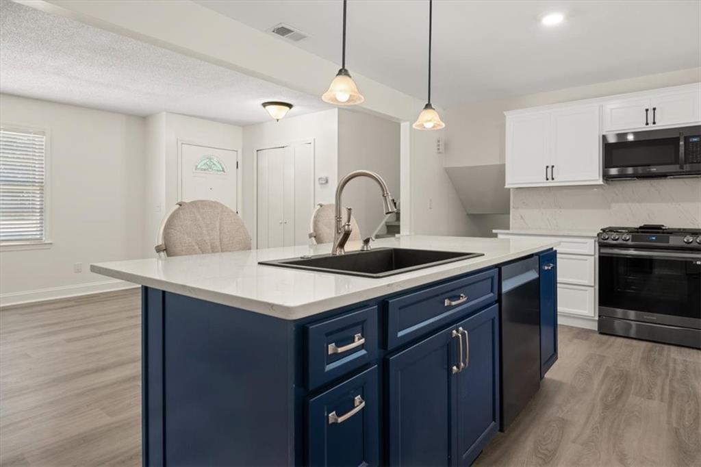 a kitchen with stainless steel appliances granite countertop a sink a stove and a wooden floors