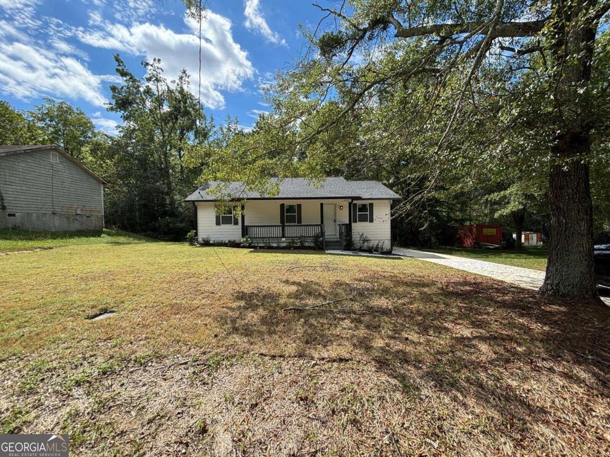 a view of house with yard and trees in the background