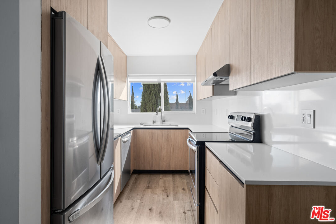 a kitchen with stainless steel appliances granite countertop a refrigerator a sink and white cabinets