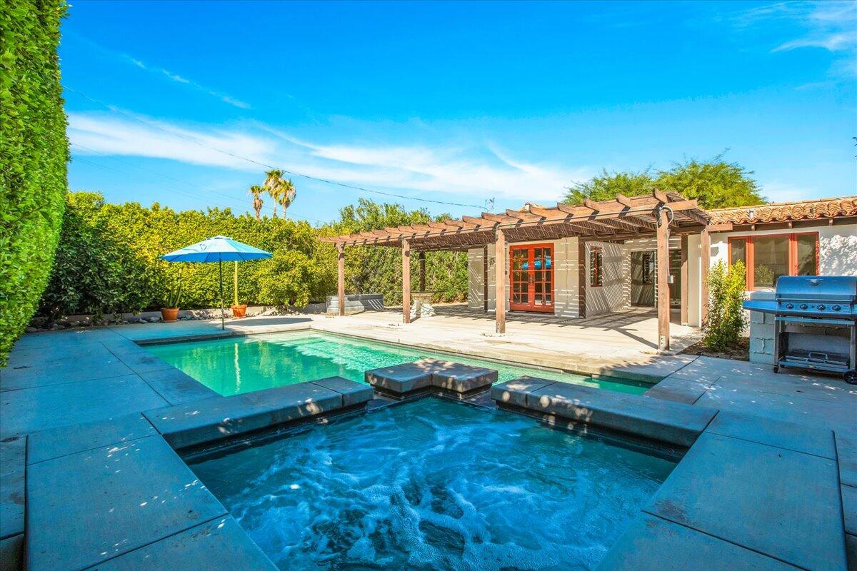 a view of swimming pool with lawn chairs under an umbrella