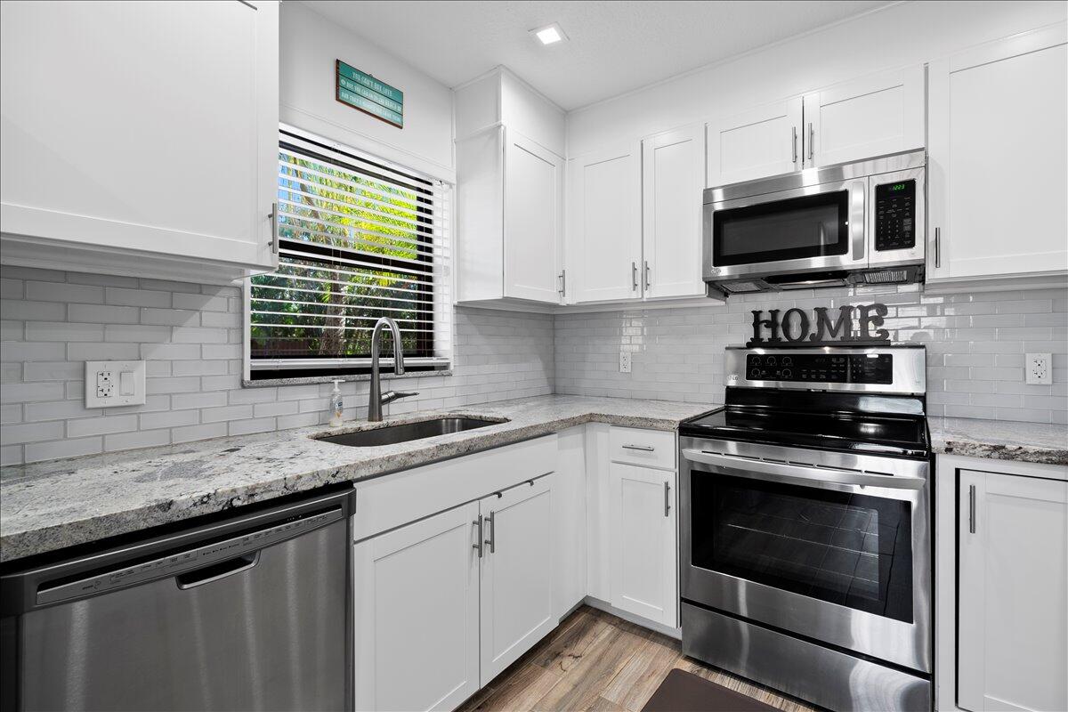 a kitchen with granite countertop a sink stainless steel appliances and a counter space