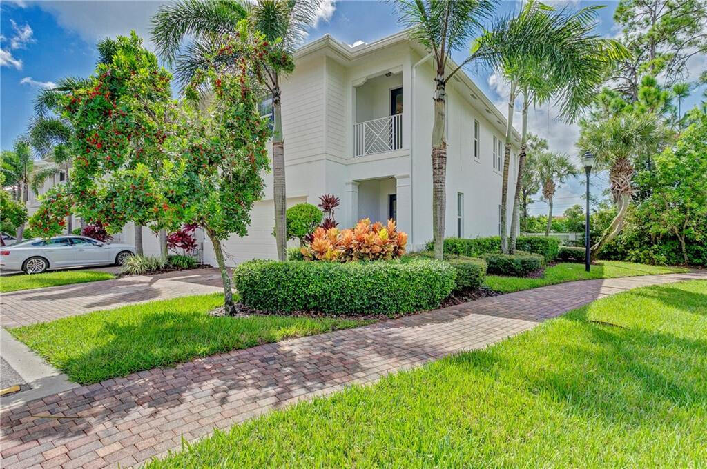 a front view of a house with a garden and trees