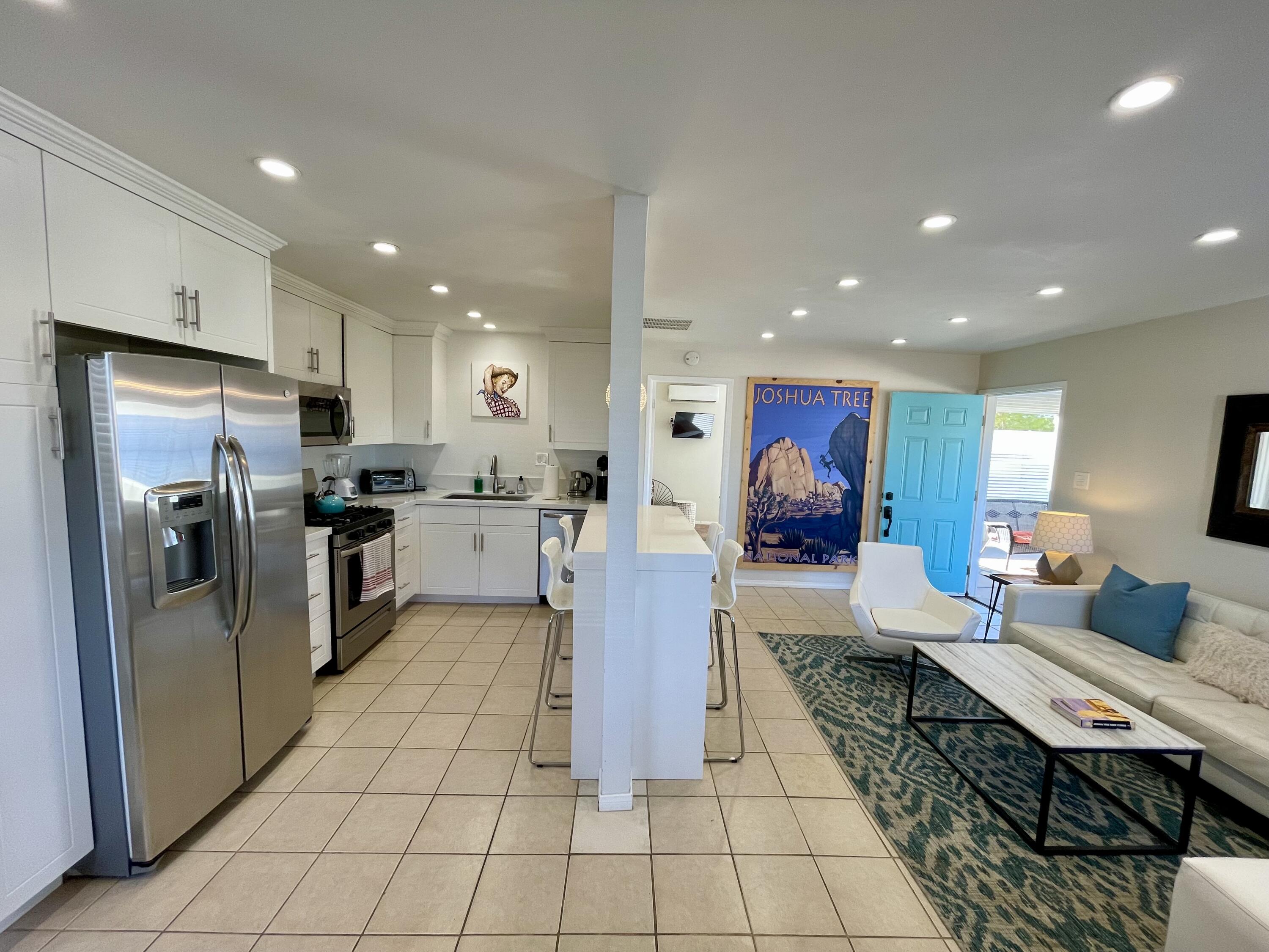 a living room with stainless steel appliances furniture and a kitchen view