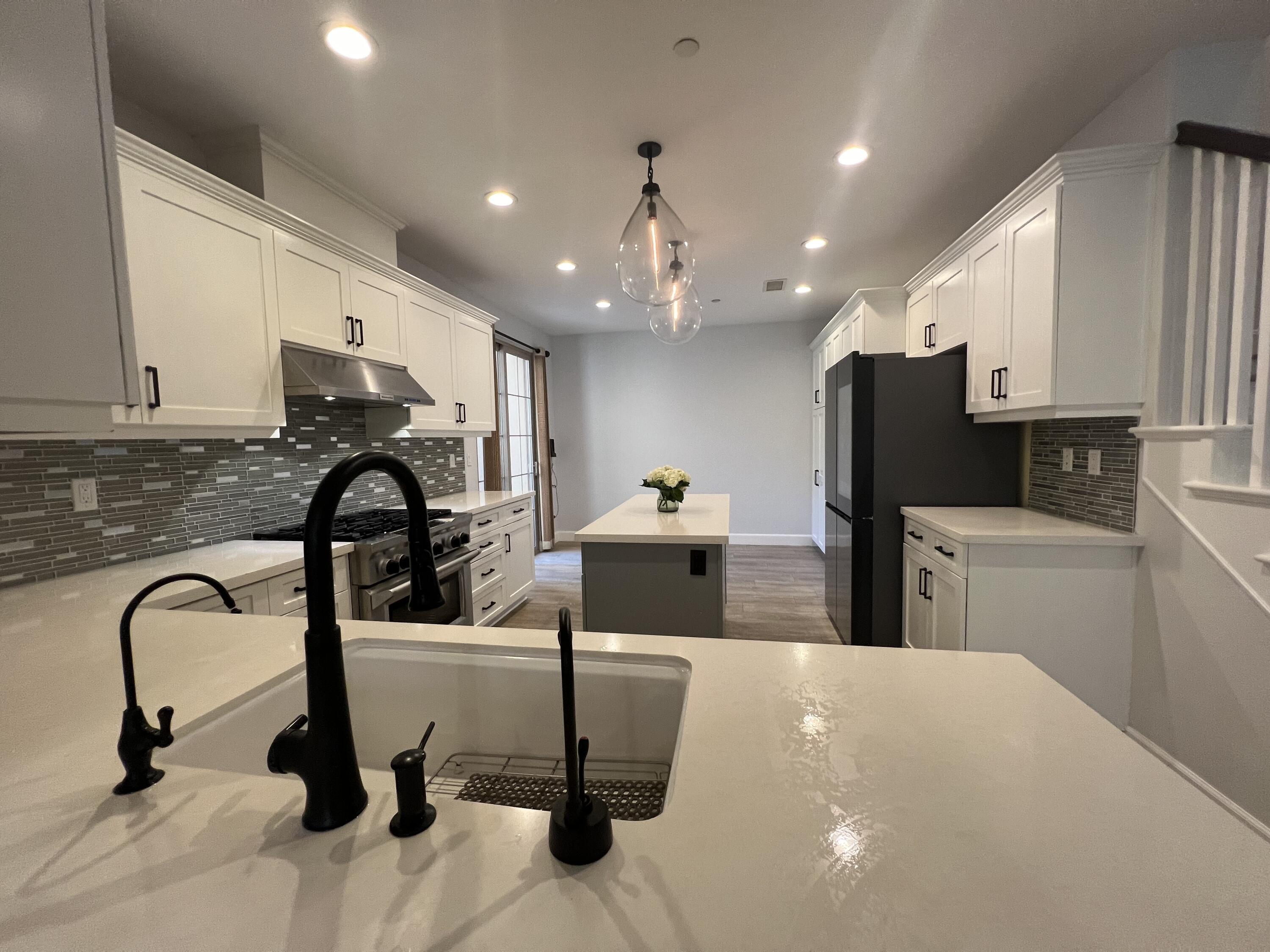 a view of a kitchen with kitchen island stainless steel appliances wooden floor dining table and chair