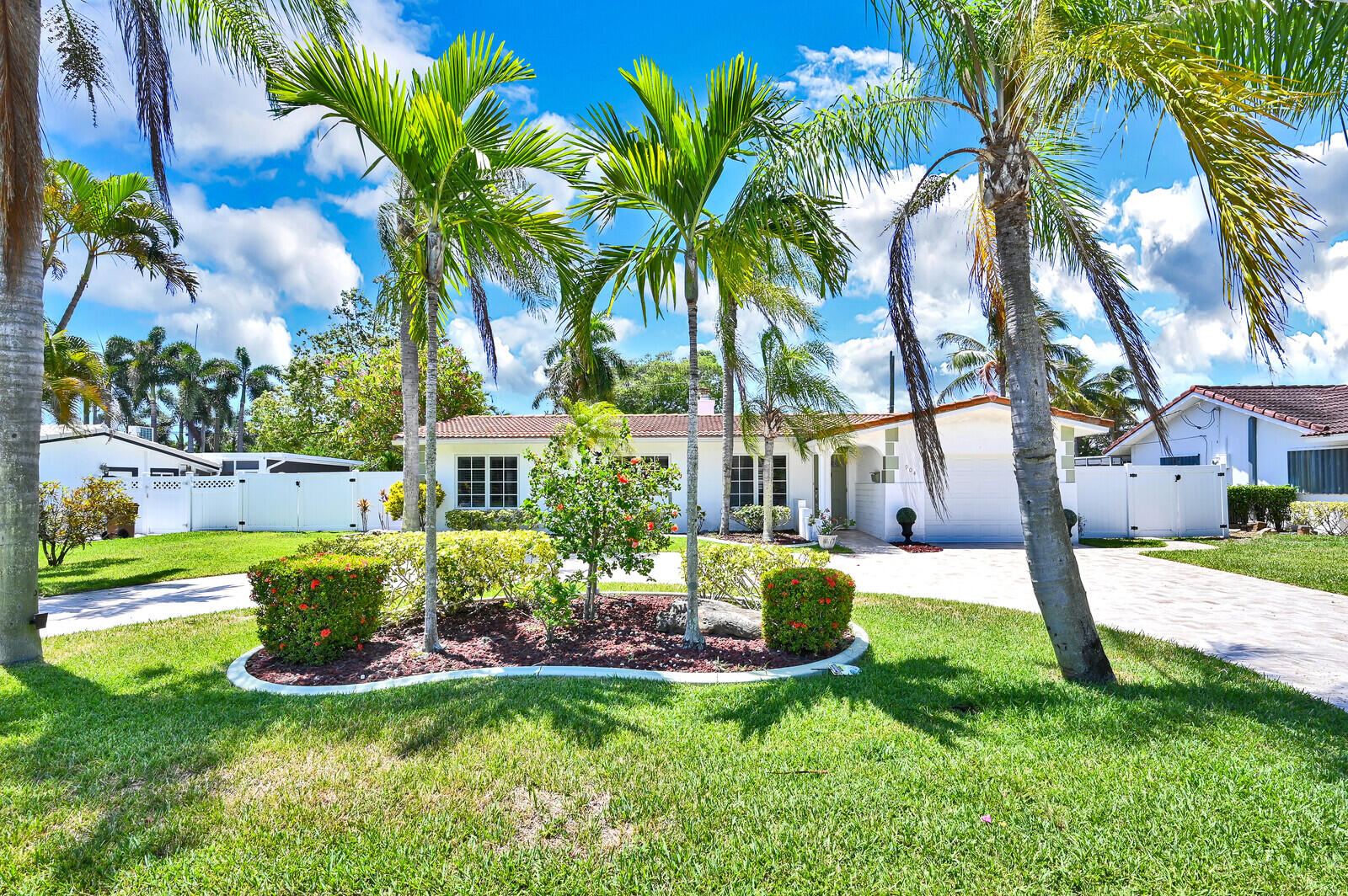 a view of a house with a yard and palm trees