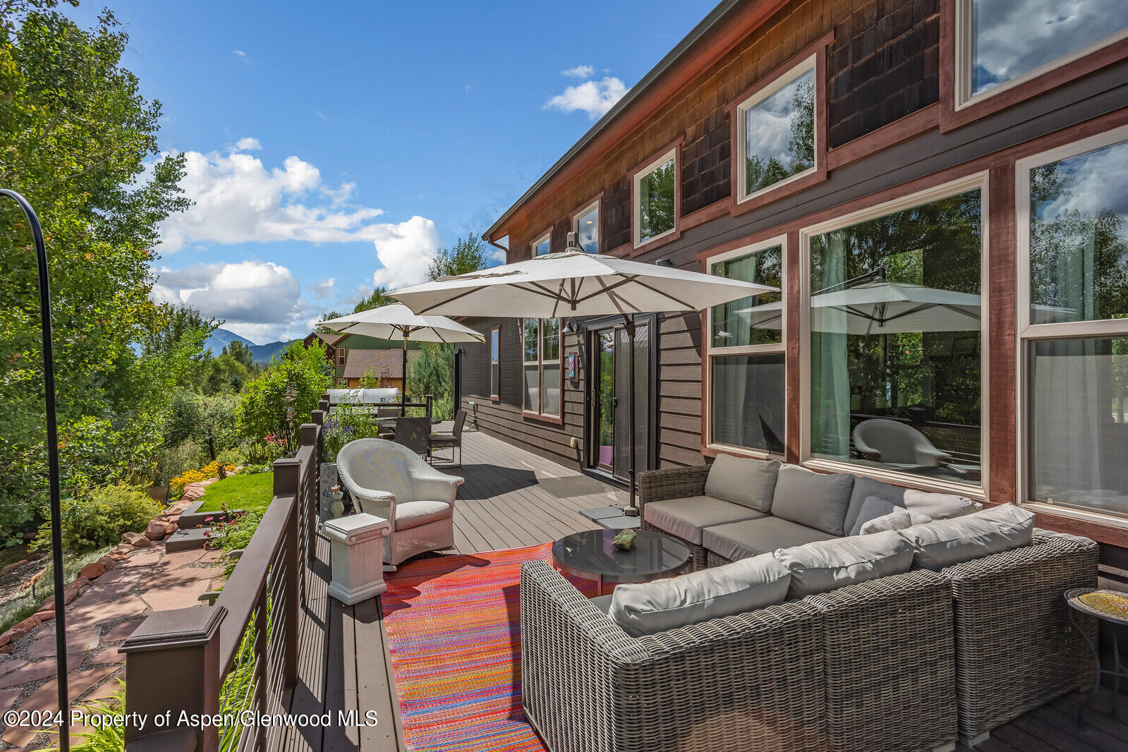 a view of a patio with couches table and chairs under an umbrella with a fire pit