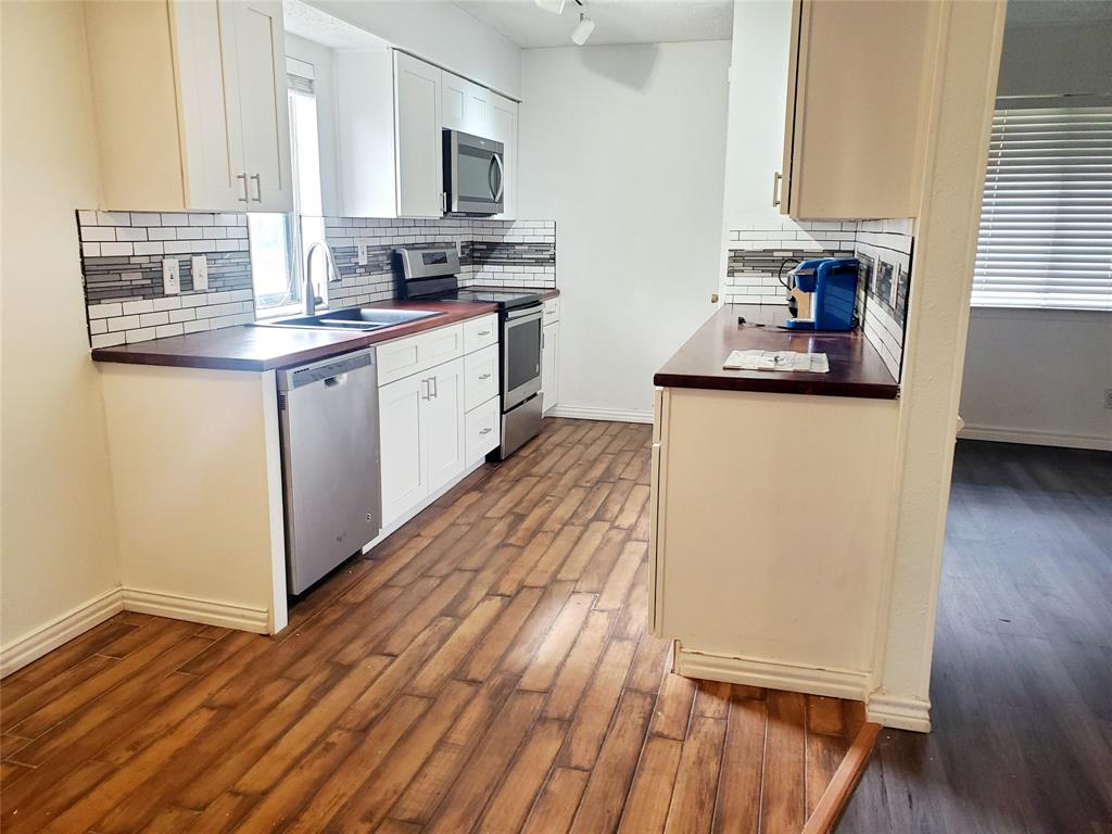 a kitchen with granite countertop a sink cabinets and wooden floor