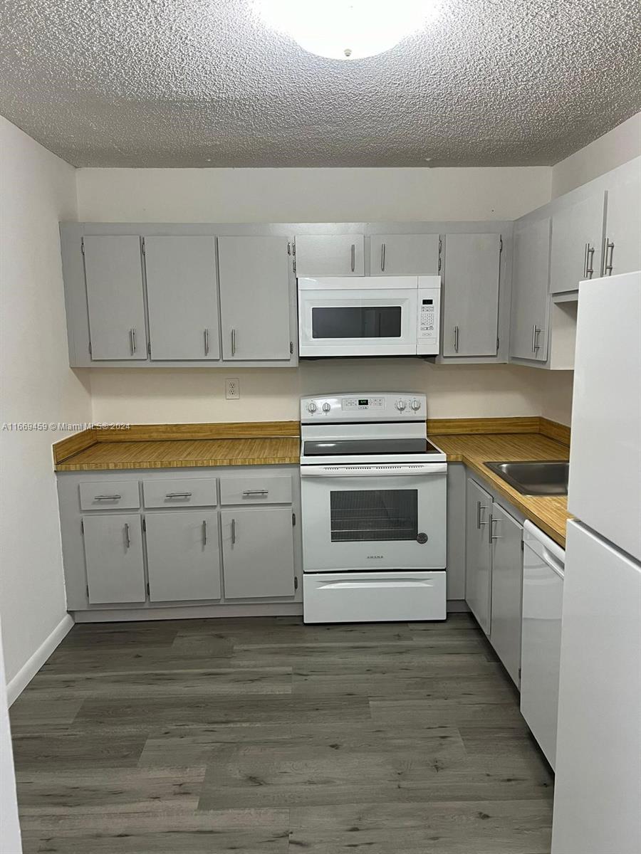 a kitchen with cabinets appliances and a wooden floor