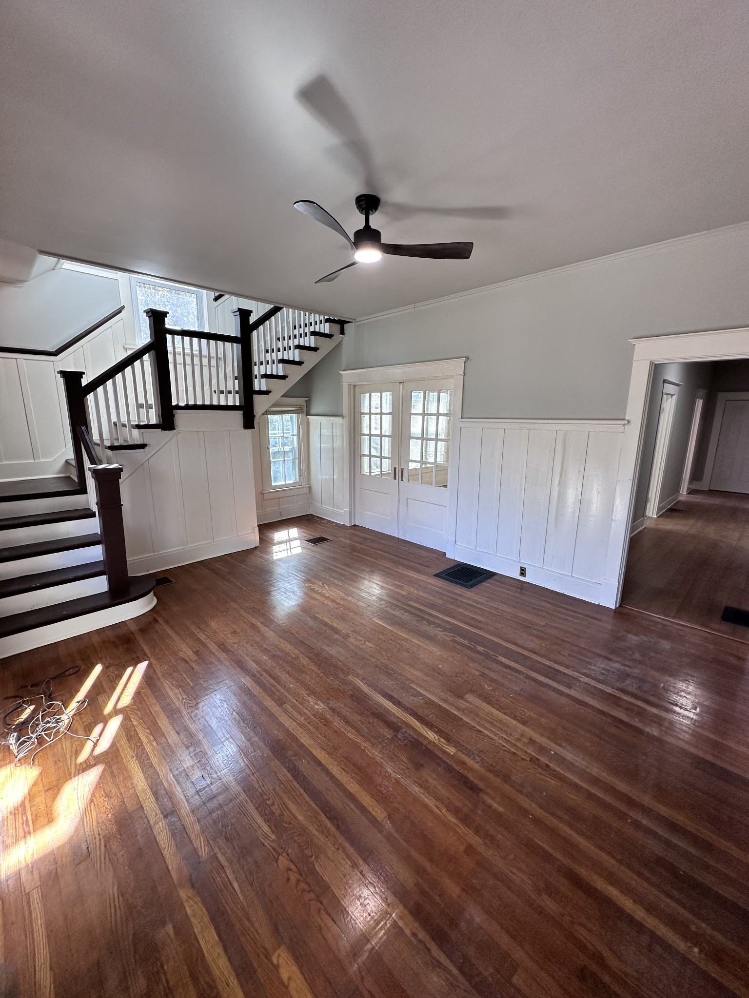 a view of empty room with wooden floor and fan