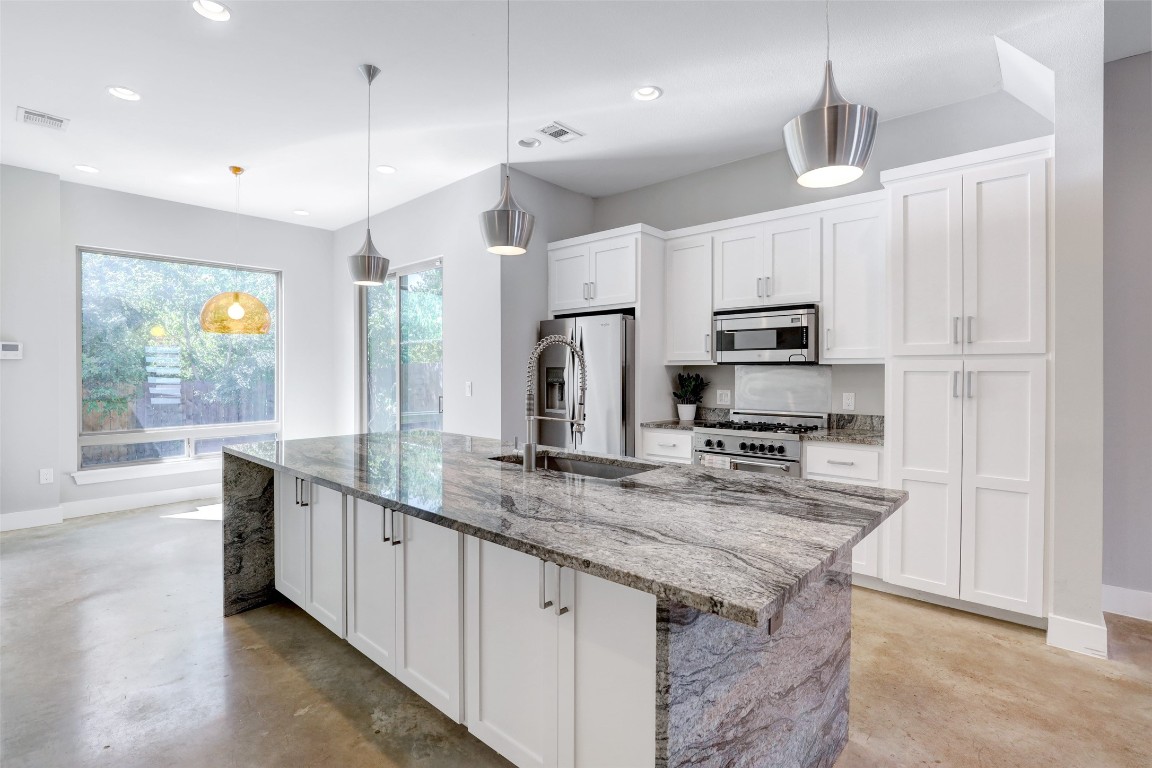 a kitchen with stainless steel appliances granite countertop a sink a stove a microwave a center island and cabinets