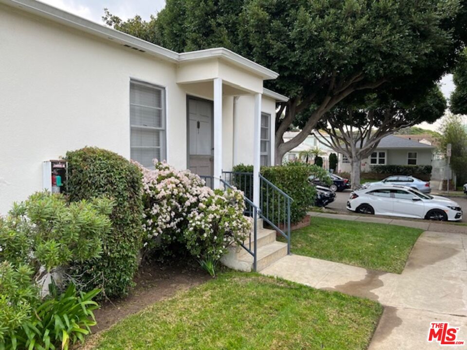 a view of a white house with a yard and potted plants