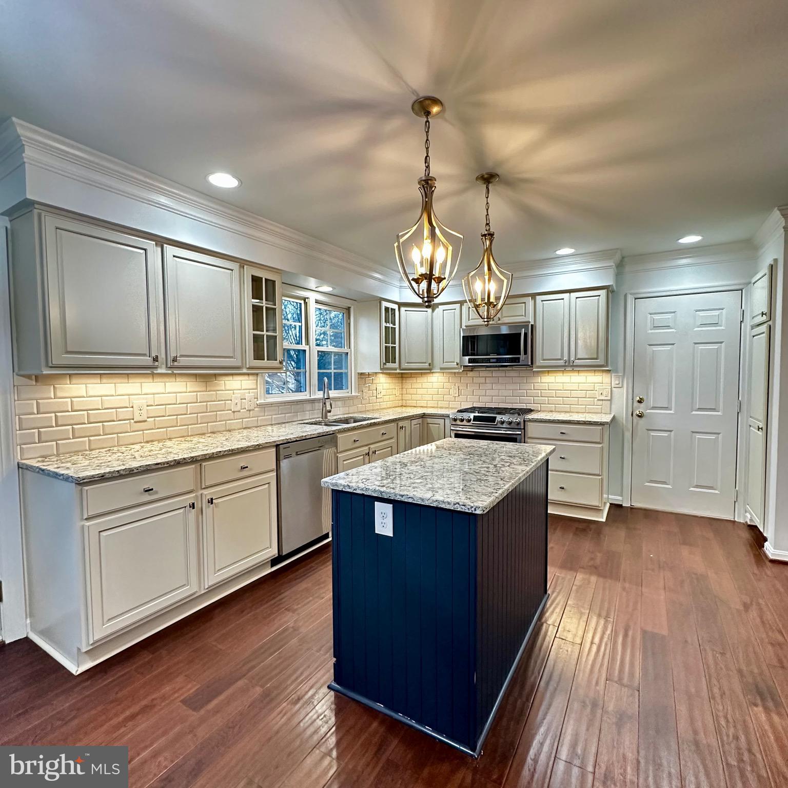 a kitchen with stainless steel appliances granite countertop wooden floors and white cabinets