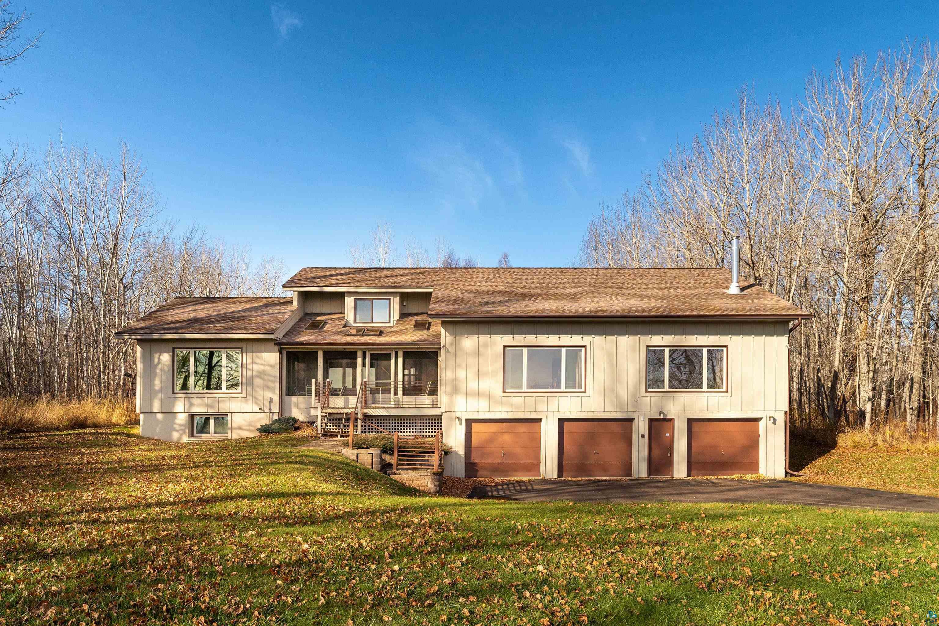 View of front of home with a sunroom, a front yard, and a garage