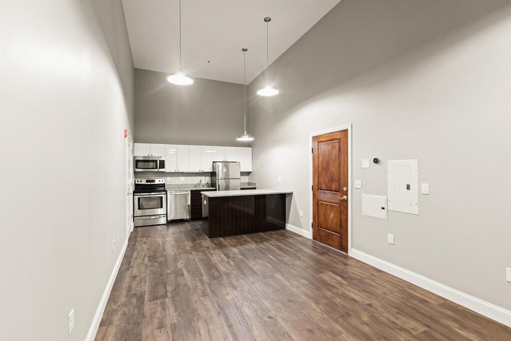 a large kitchen with a center island wooden floor and stainless steel appliances