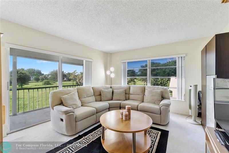 a living room with furniture a large window and a flat screen tv