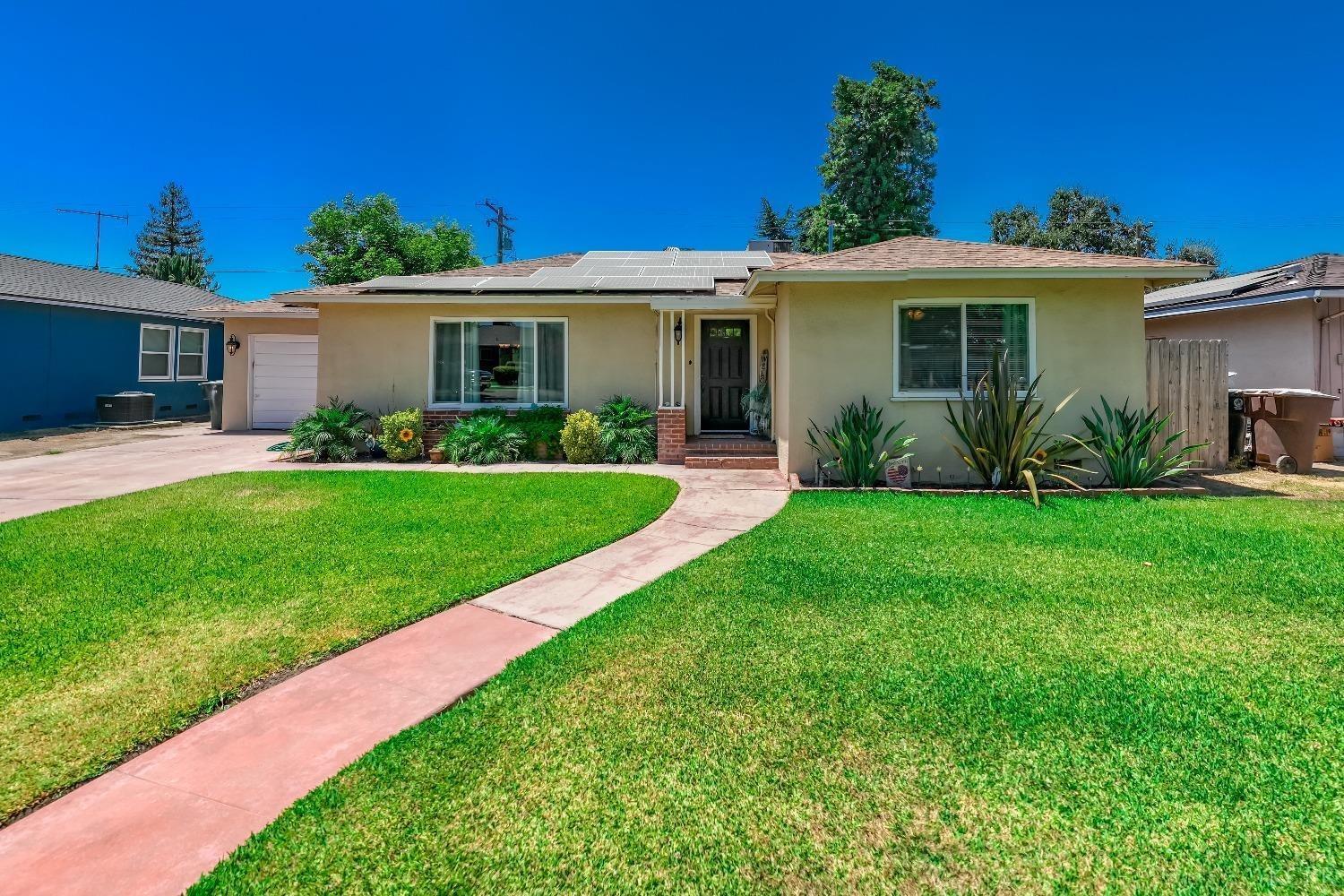 a front view of a house with a yard and potted plants