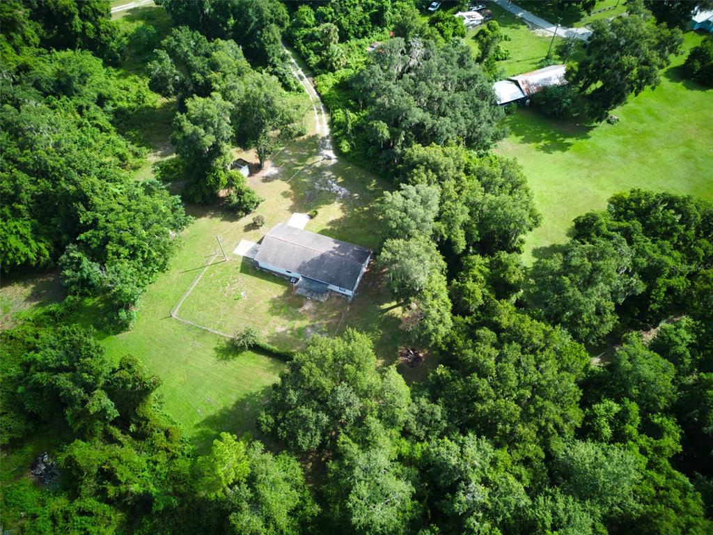 an aerial view of residential house with outdoor space and trees all around