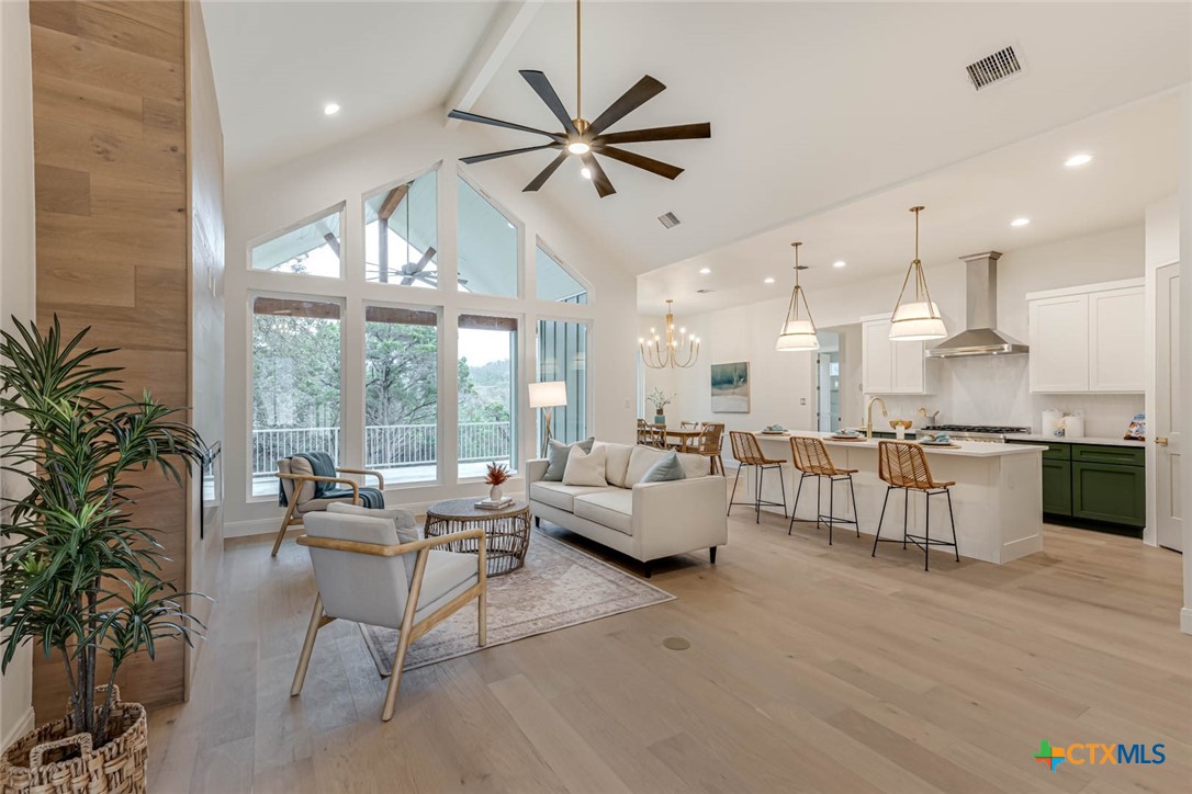 a living room with furniture kitchen area and a large window