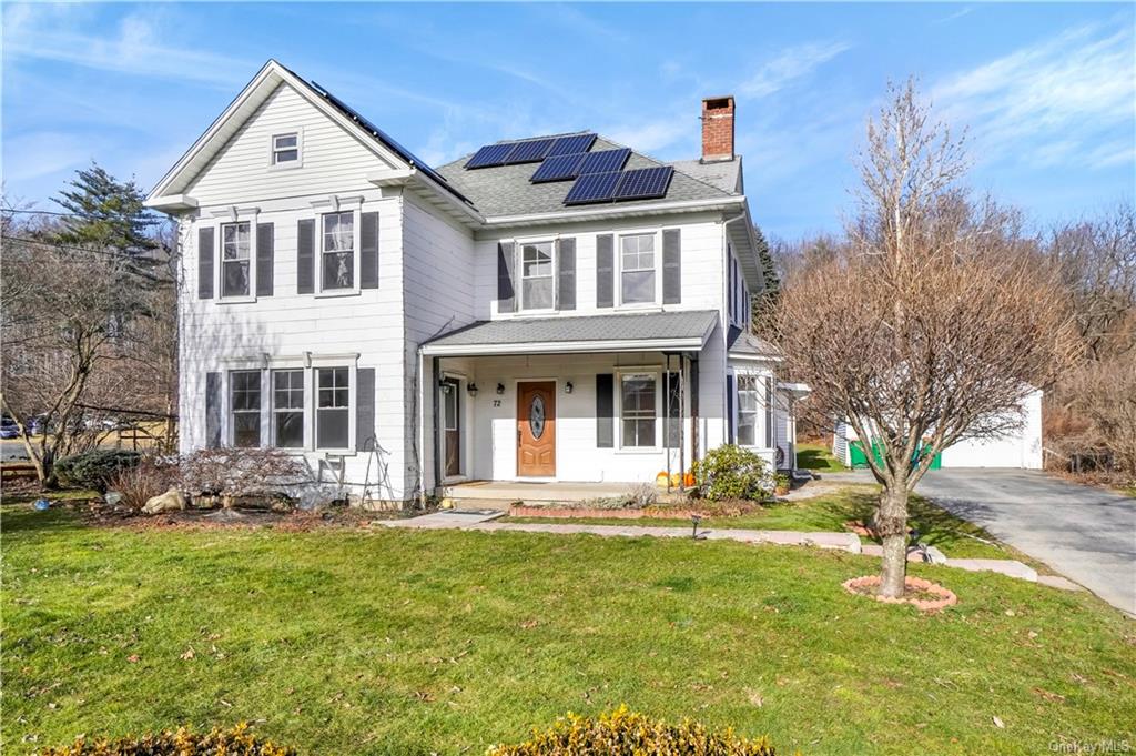 Front of property with a front lawn, solar panels, a porch, and a garage