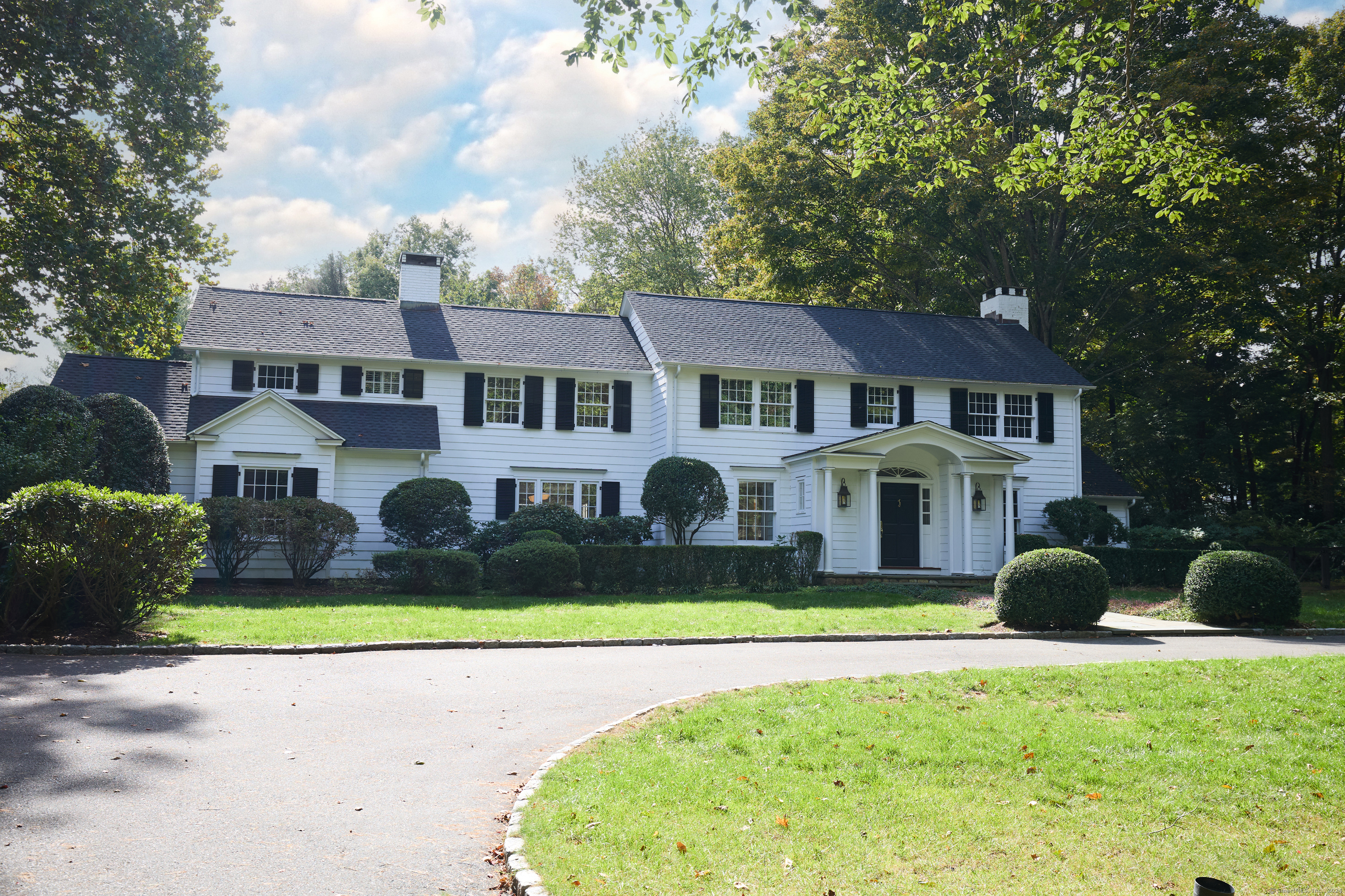 a front view of a house with a garden and trees