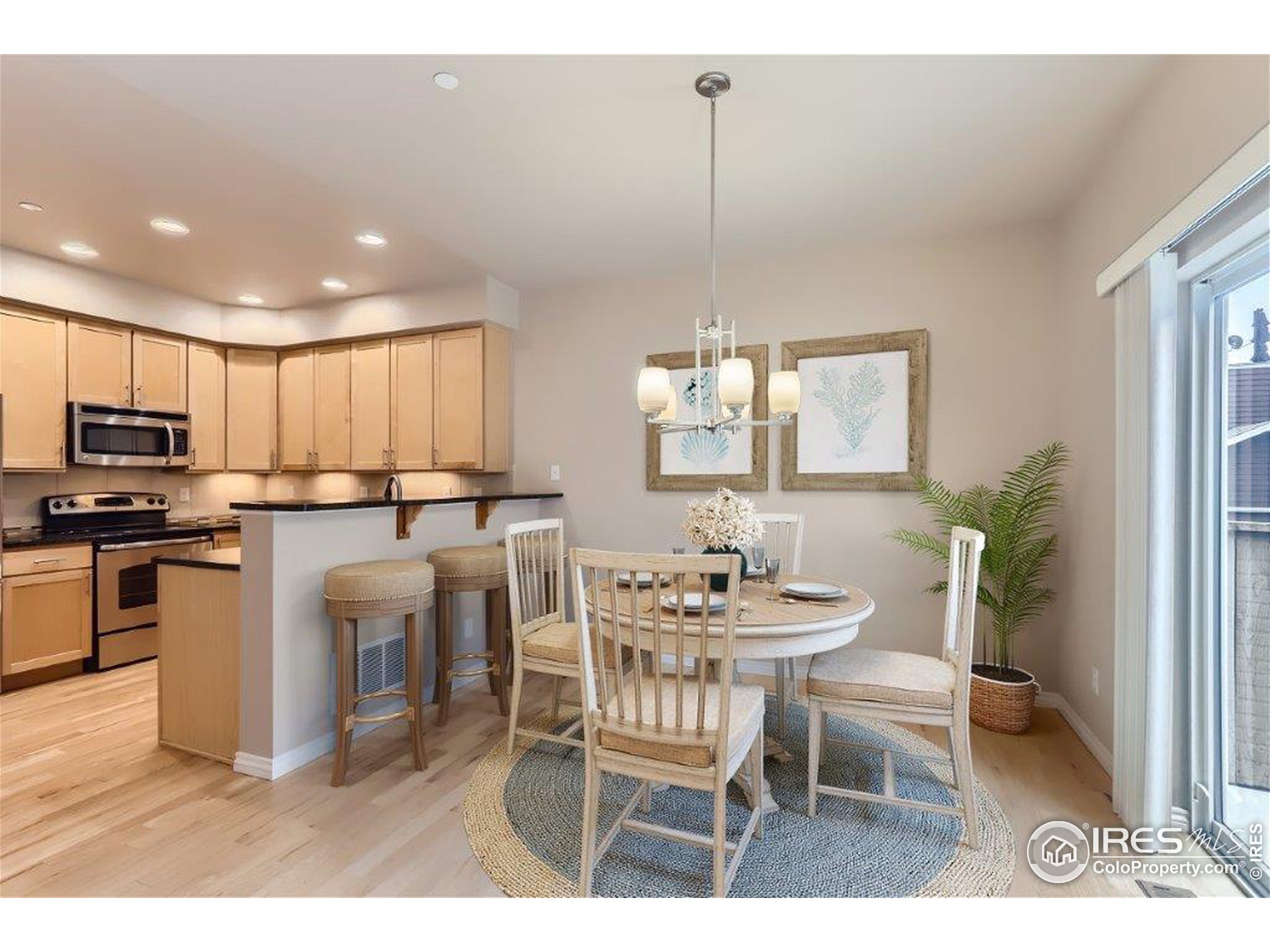 a kitchen with stainless steel appliances kitchen island granite countertop a dining table chairs and white cabinets