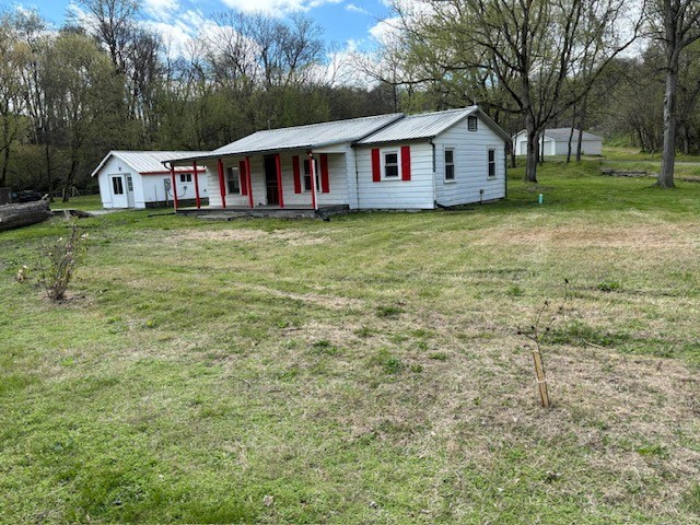 a view of house with outdoor space and trees in the background