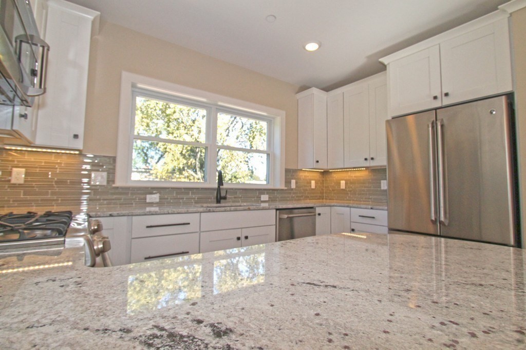 a large kitchen with granite countertop a stove a sink a refrigerator and window