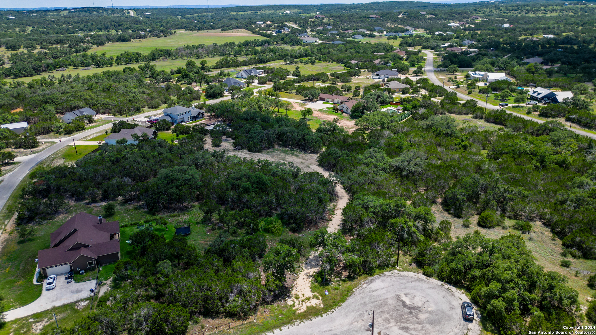 an aerial view of residential houses with outdoor space and trees