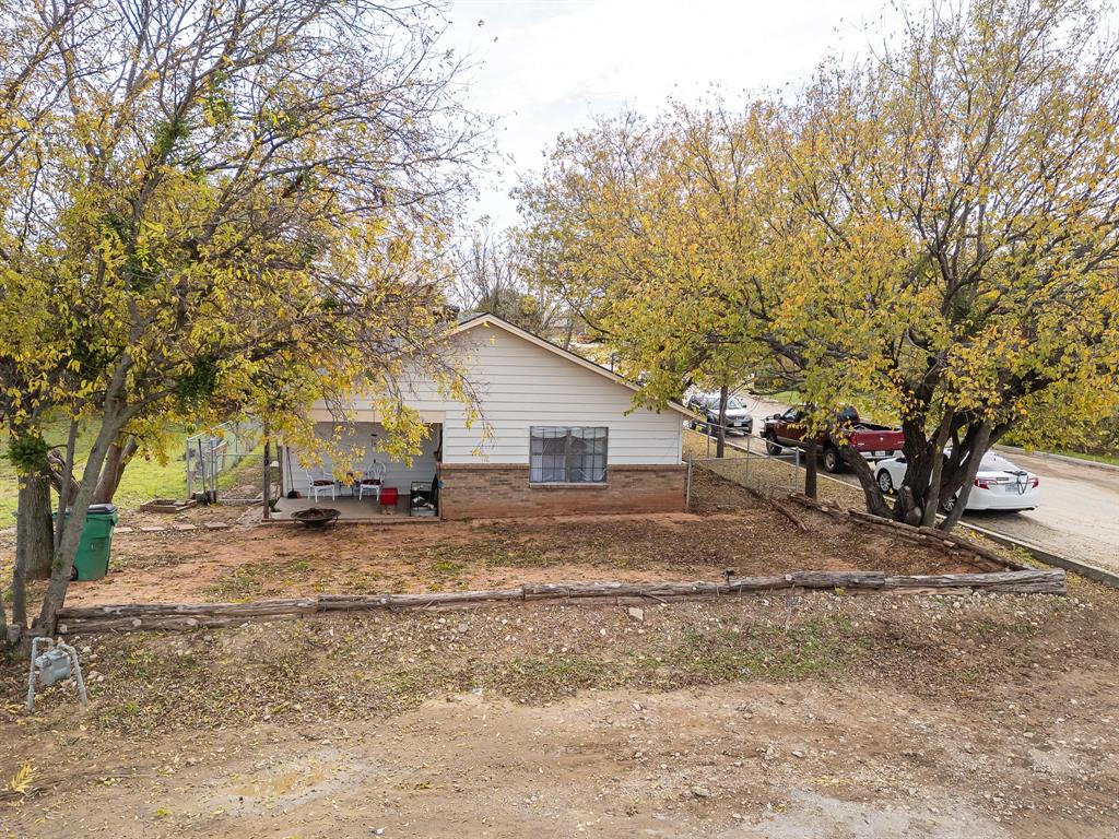 a view of a yard with a large tree and wooden fence