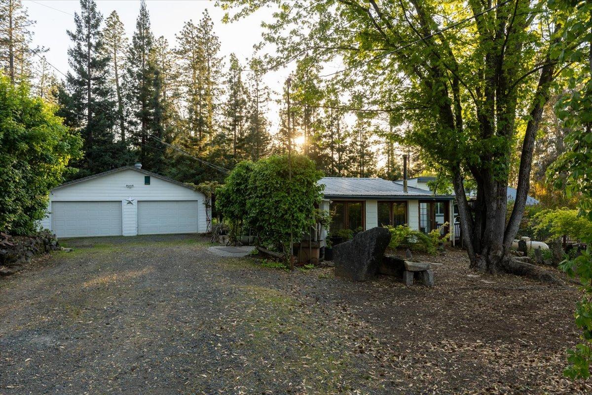 a view of a house with a yard and large trees