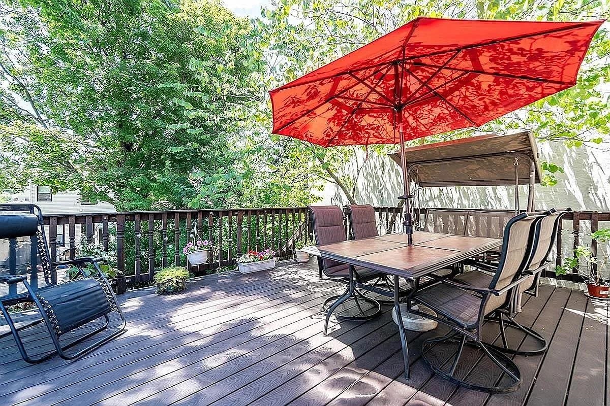 a patio with wooden floor a yard a table and chairs