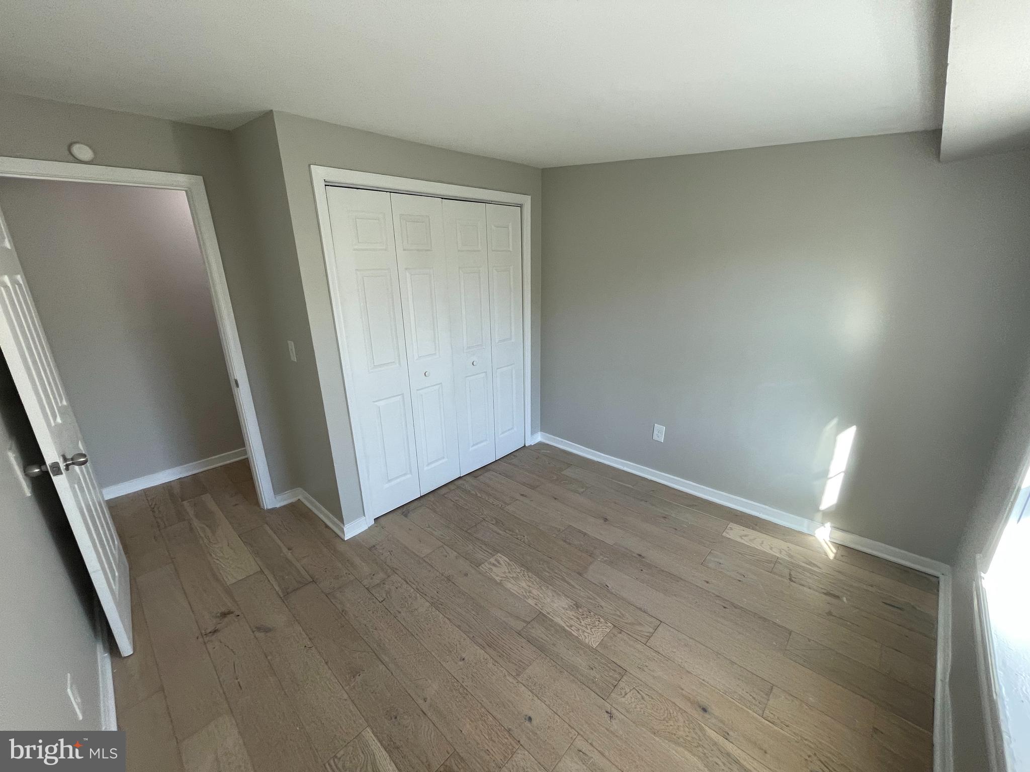 an empty room with wooden floor and entrance