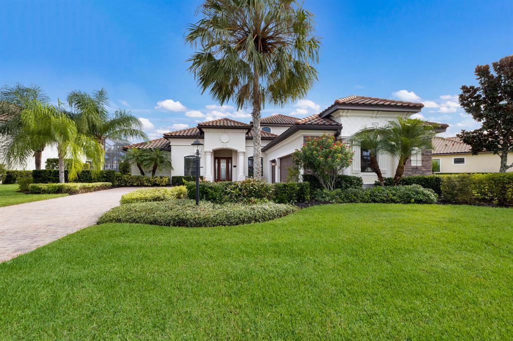 a view of a white house with a big yard and potted plants