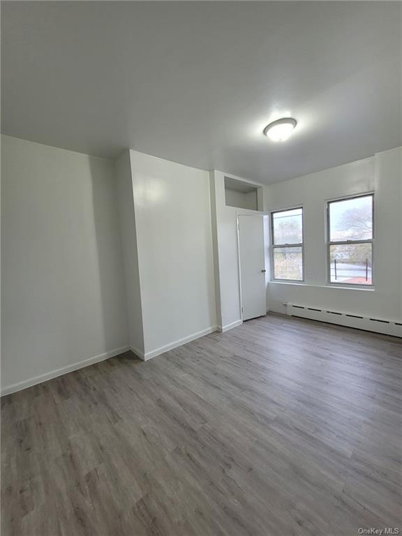 Bedroom with a baseboard radiator and light wood-type flooring