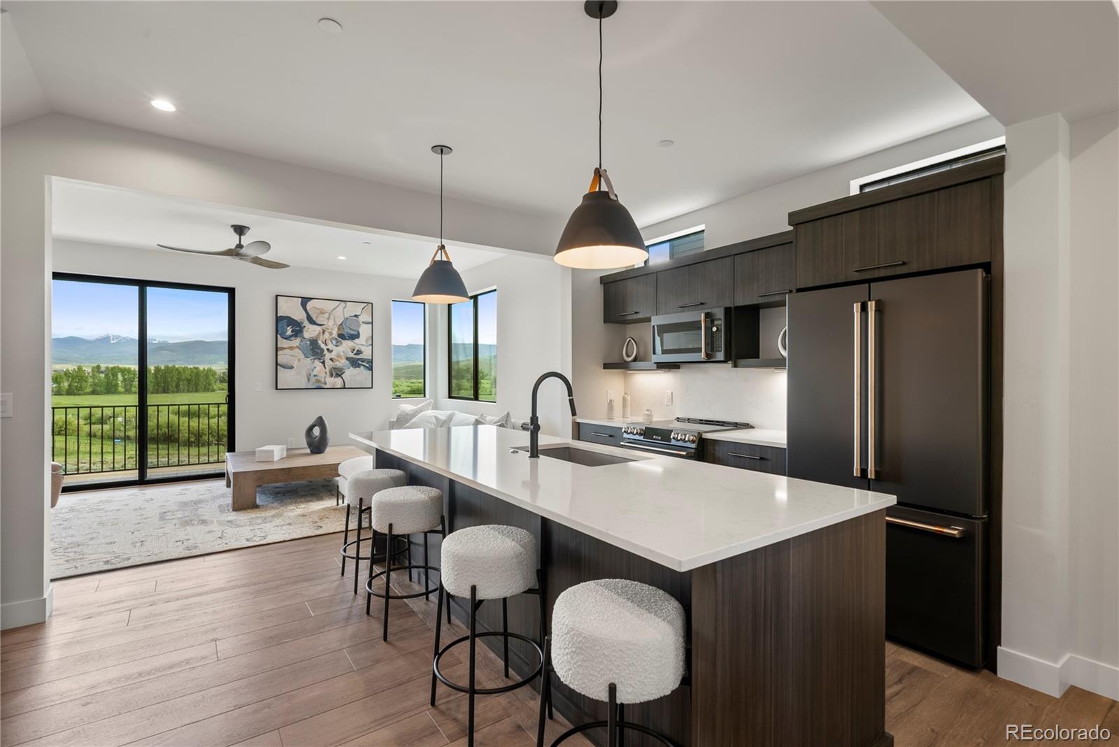 a open kitchen with stainless steel appliances granite countertop a stove a refrigerator a sink dishwasher a dining table and chairs with wooden floor