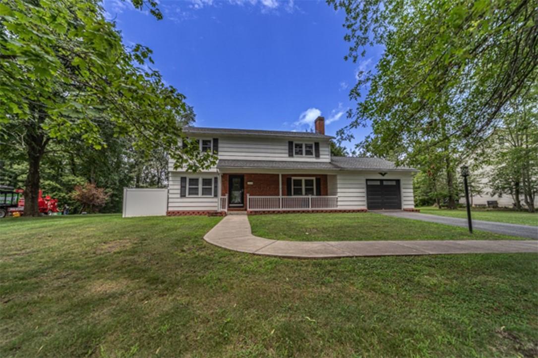 View of front of home with a garage, a front yard, and covered porch