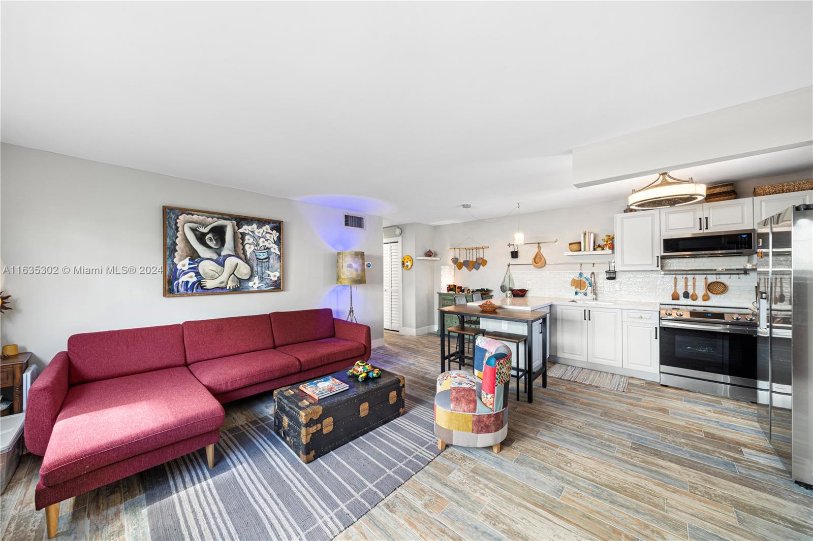 a living room with furniture kitchen view and a wooden floor