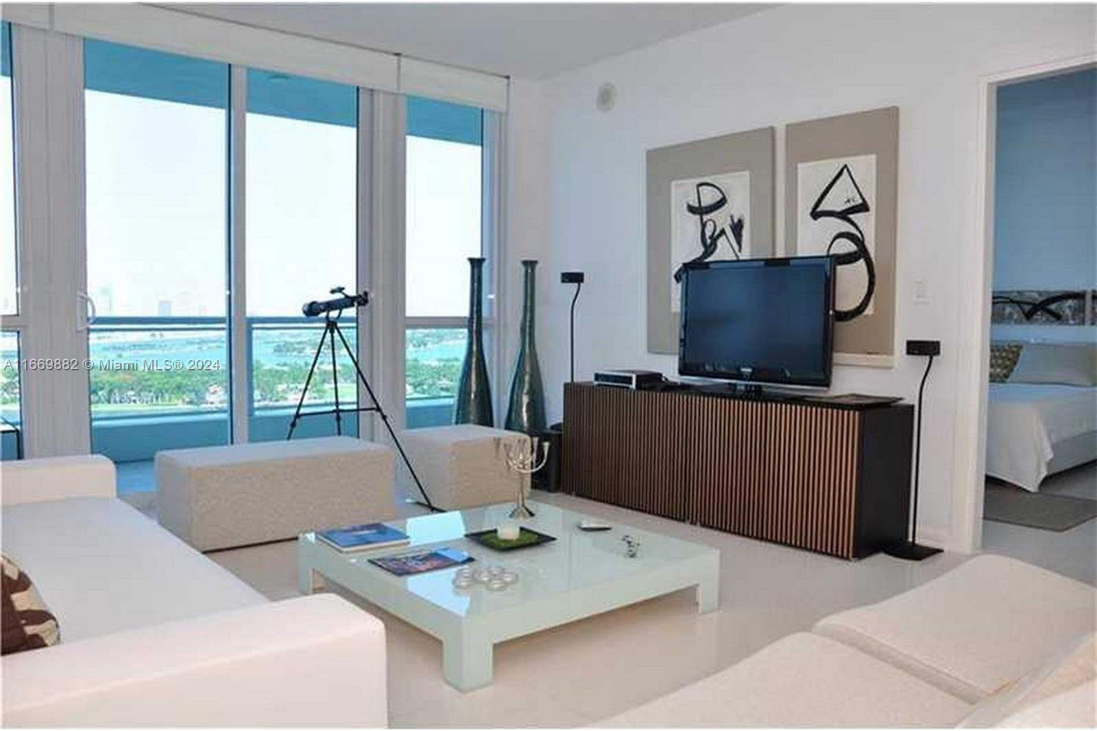 a living room with furniture a flat screen tv and a floor to ceiling window