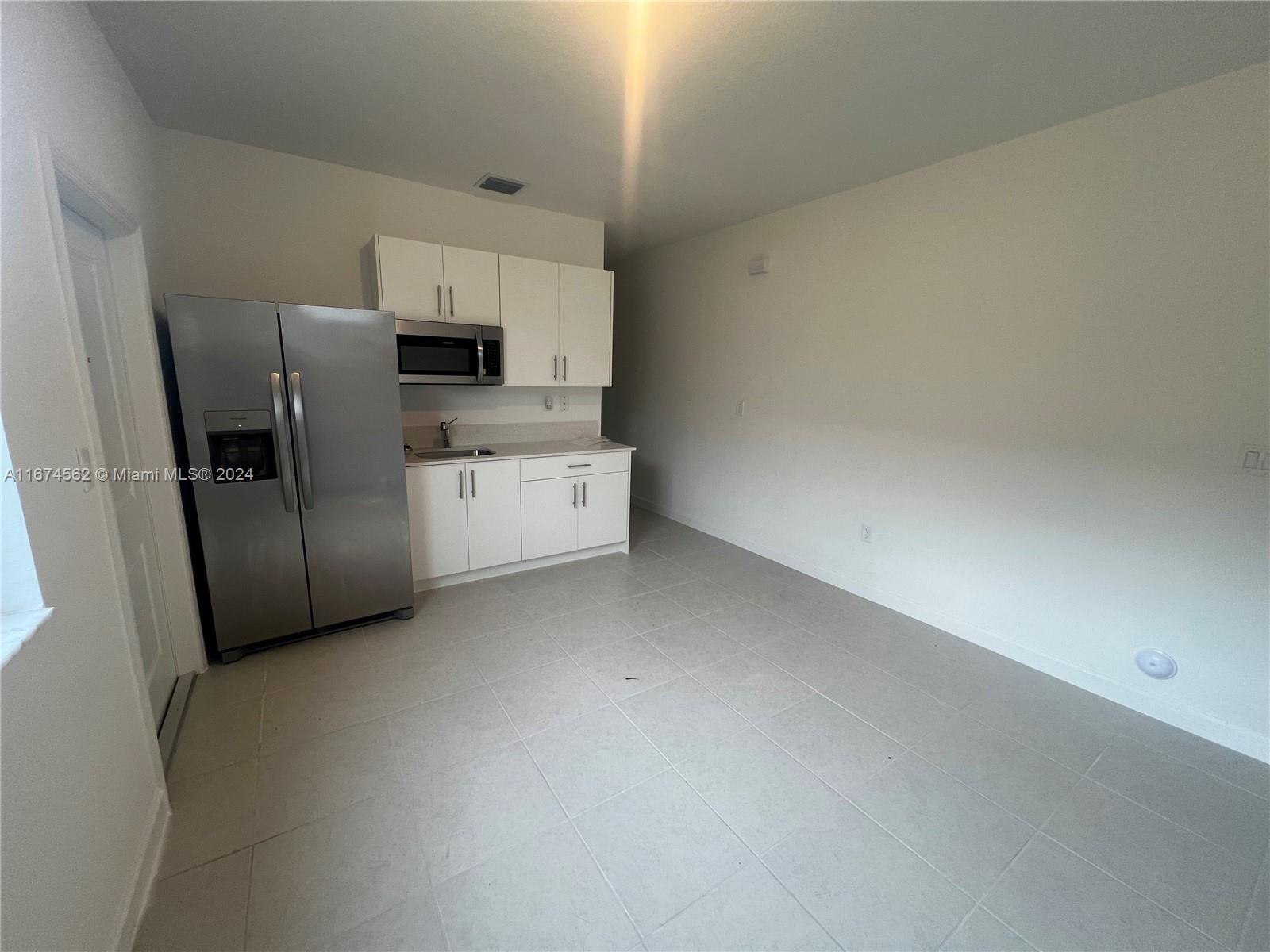 a view of a refrigerator in kitchen and an empty room